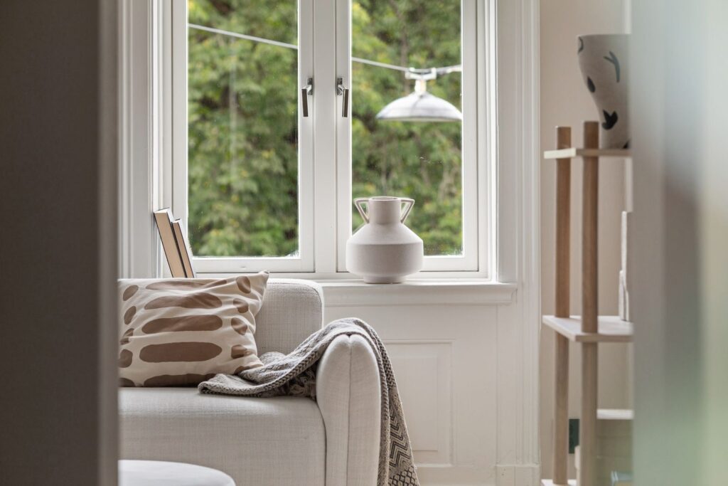 Warm, homely living room with a sofa beside large windows